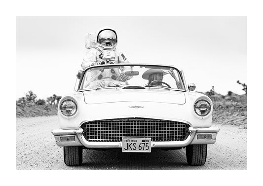 Black and white photography of an astronaut and a cowgirl going for a ride in a 1957 ford thunderbird. 