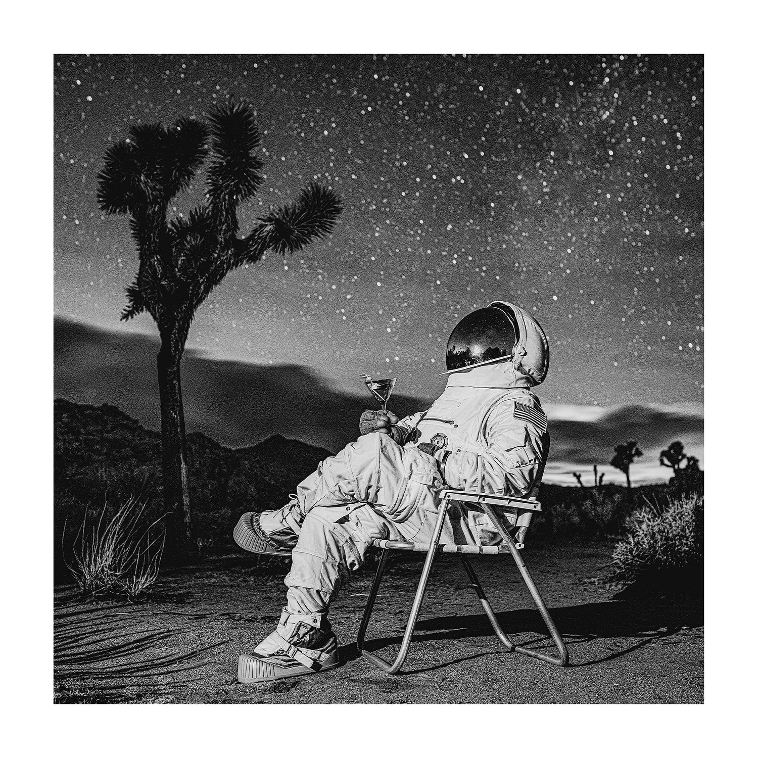 Astronaut sitting in a midcentury lawn chair under a starry night sky while drinking a martini. 